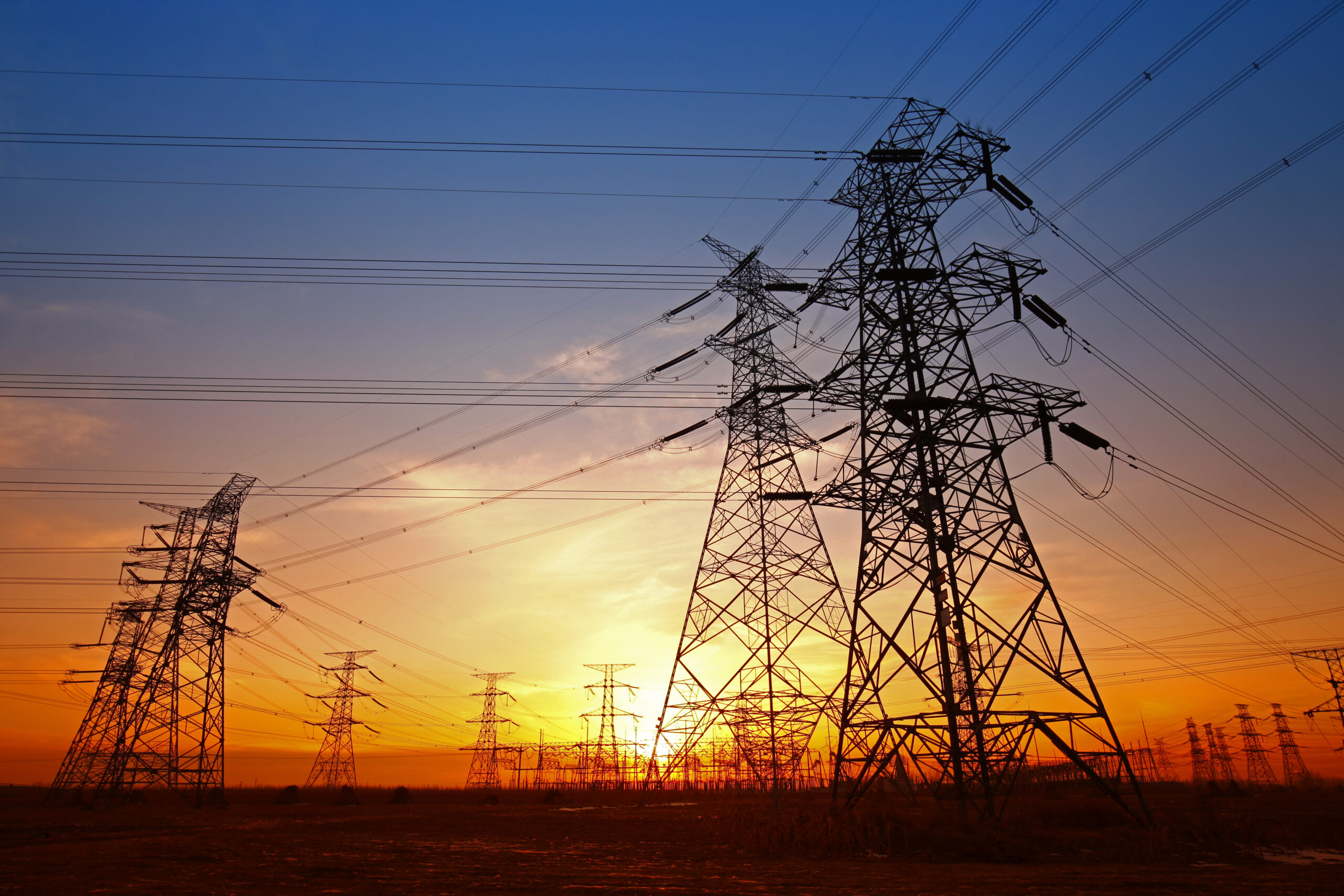 Hochspannungsmasten und Stromleitungen im Sonnenuntergang